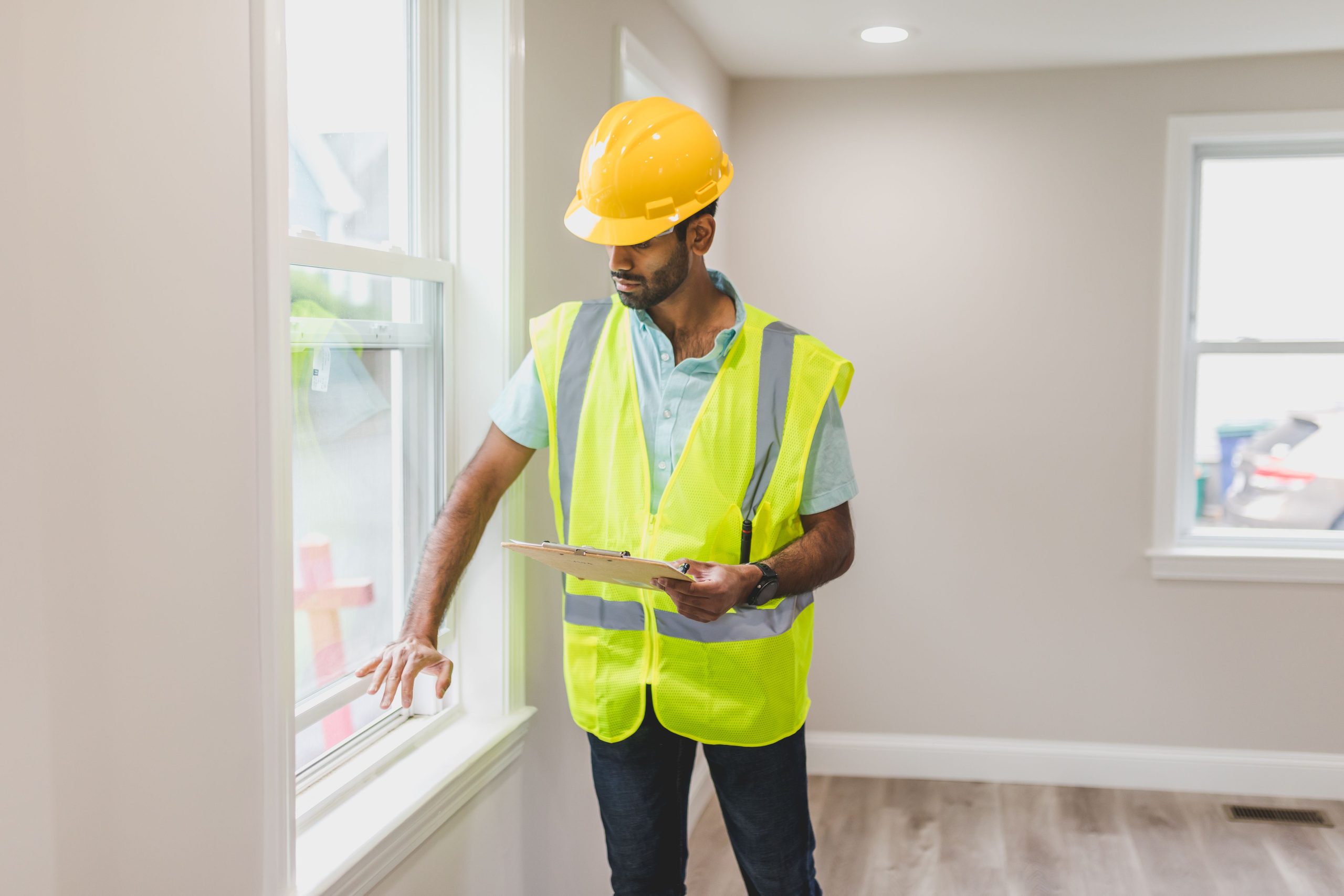 Agent immobilier inspecte une fenêtre en gilet de sécurité