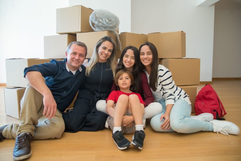 Famille souriante avec cartons dans leur nouveau logement