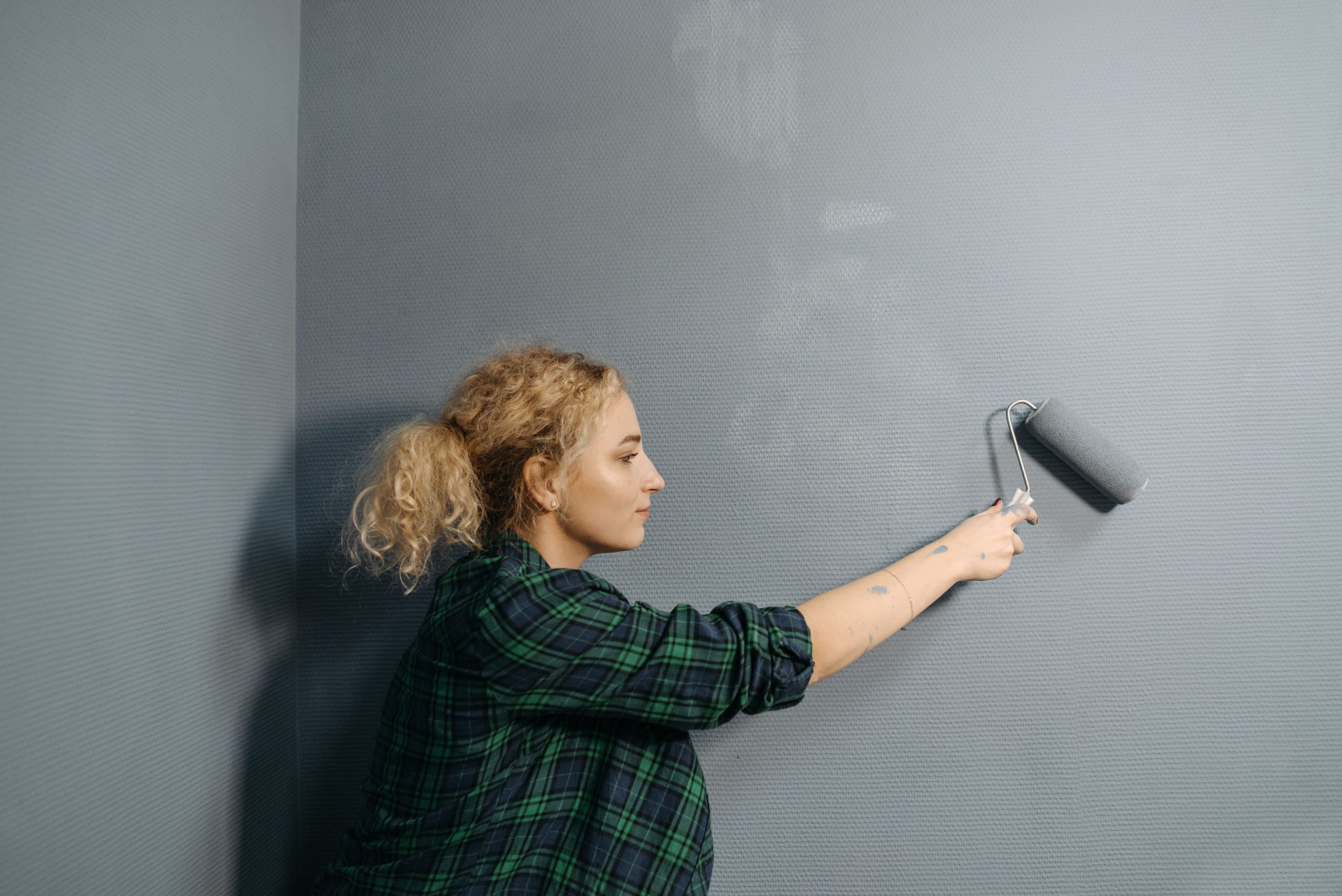 Jeune femme peignant un mur gris au rouleau